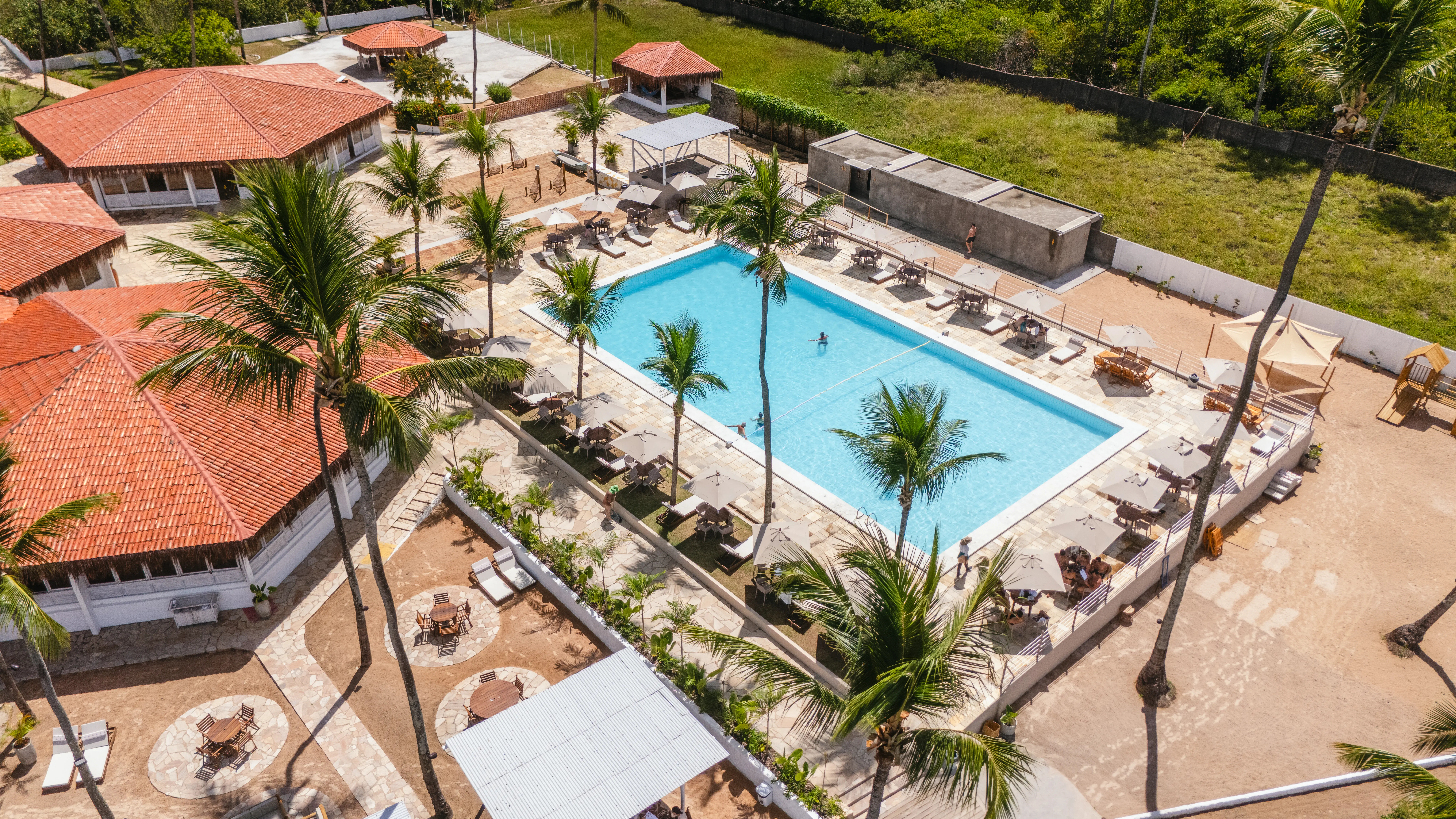 Vista aérea da piscina cercada por coqueiros no Vivari Beach Club