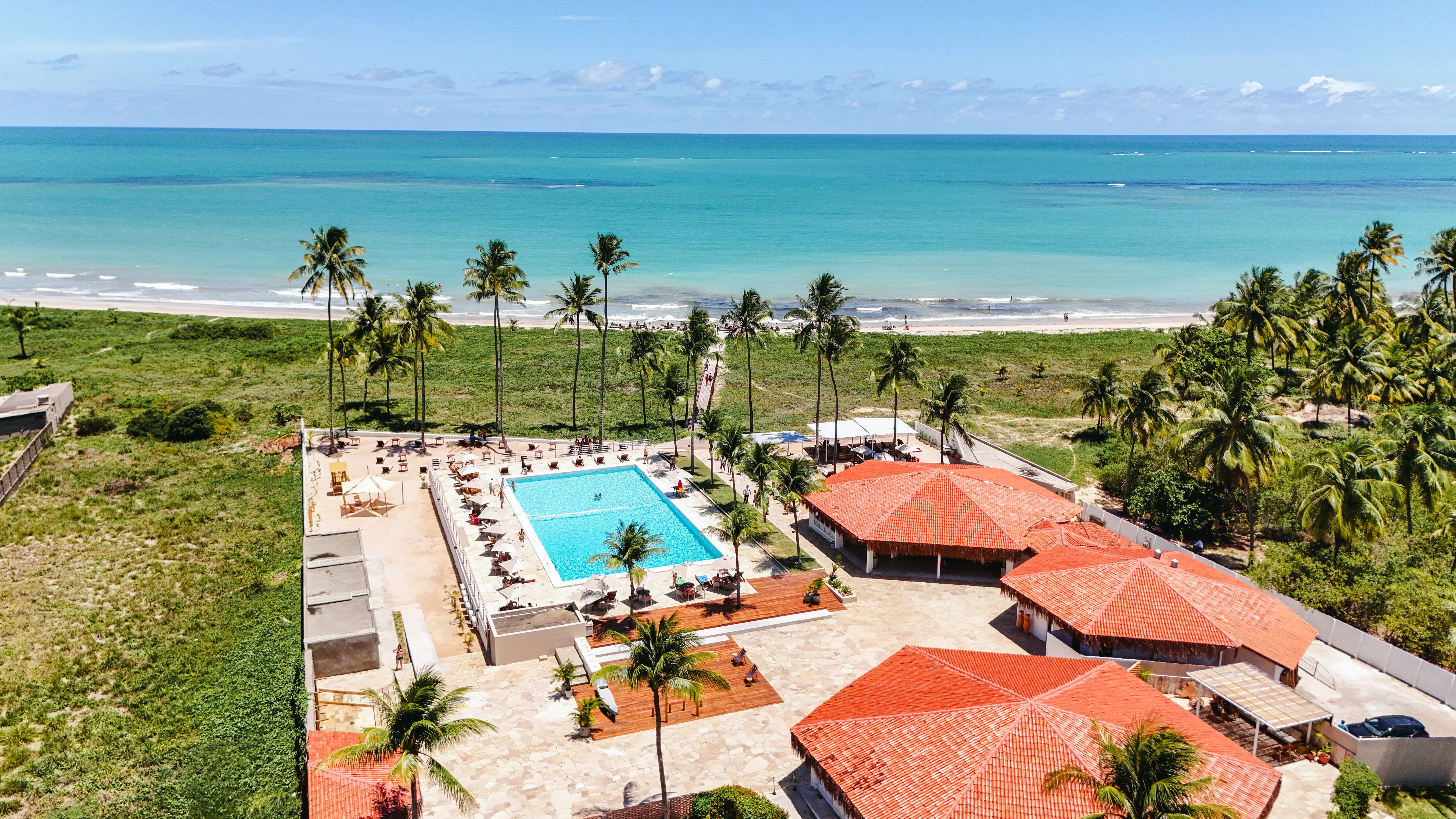 Vista aérea dos telhados, da piscina e do mar de Ipioca no Vivari Beach Club