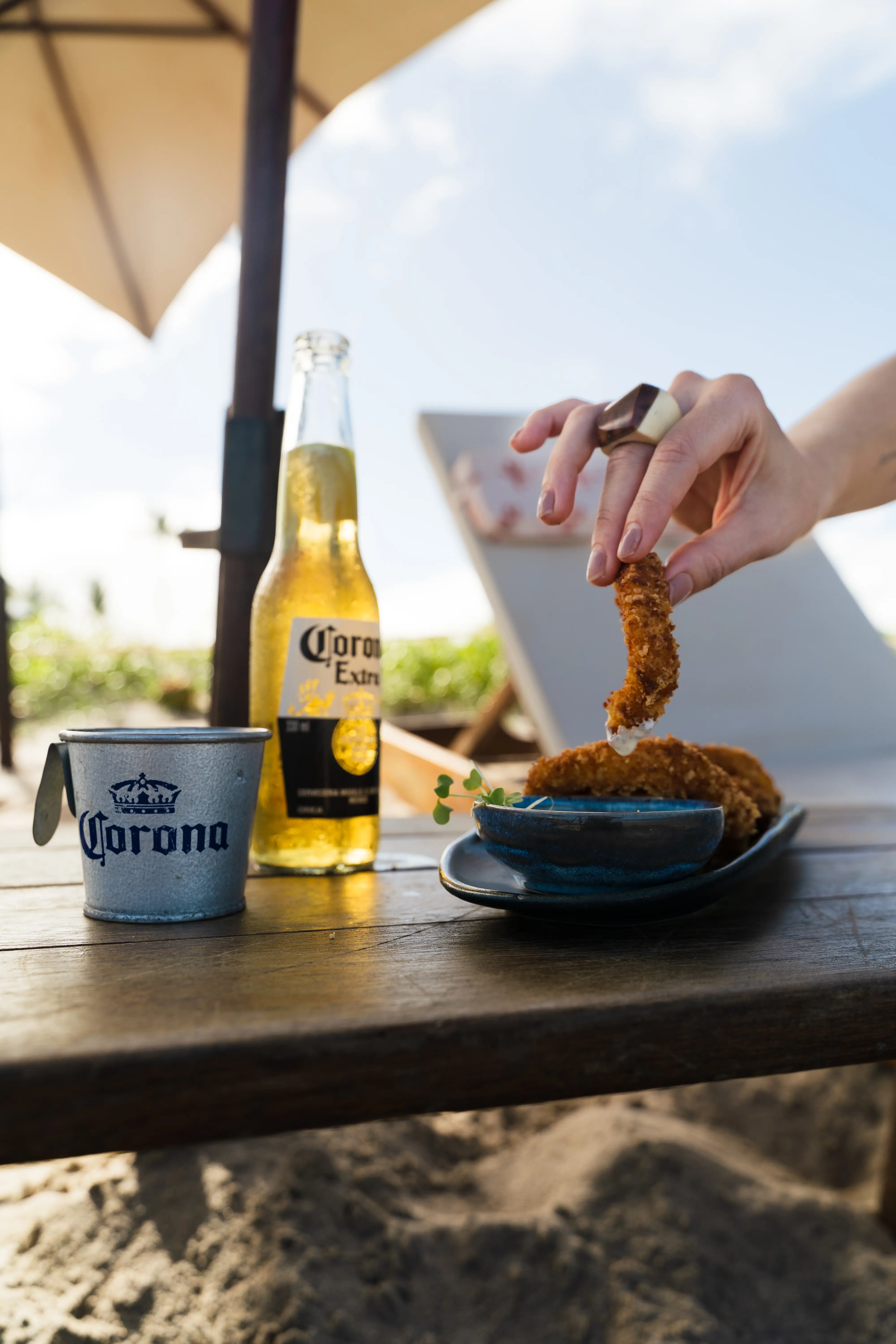 Petisco e cerveja servidos em uma mesa de praia no Vivari Beach Club