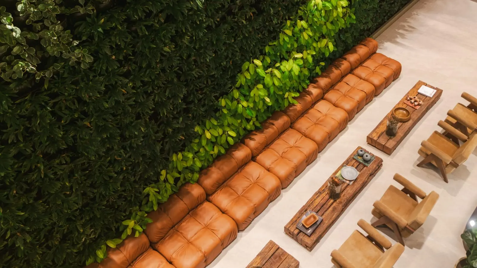 Vista aérea do sofá de couro do lobby, com parede de plantas ao fundo