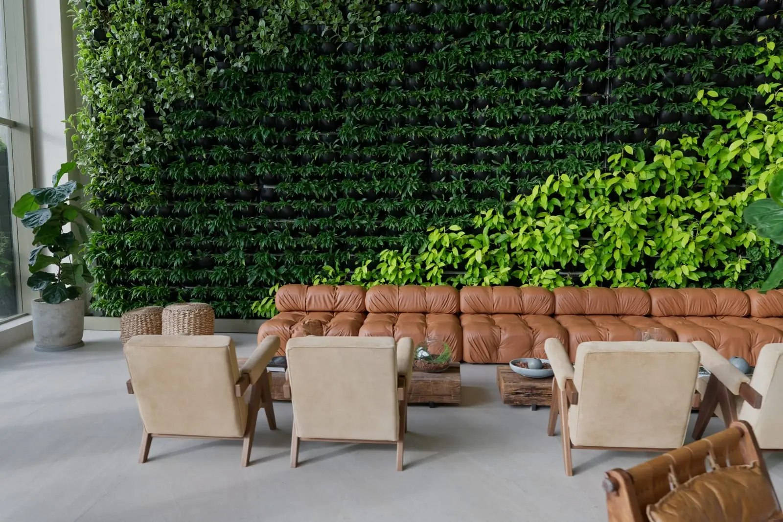 Sofá de couro e poltronas junto à parede de plantas do lobby